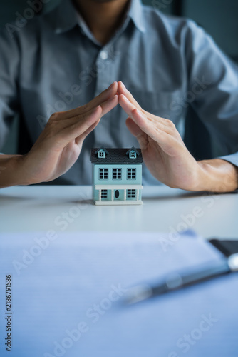 Fotografie Asian businessman holding hands protect house model, home insurance concept
