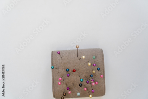 Canvastavla A clean flat lay of multiple colorful pins stuck into a beige pincushion against a white background