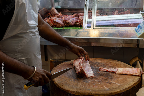 Canvastavla A skilled butcher expertly cuts and prepares fresh cuts of meat on a large wooden block in a local market setting