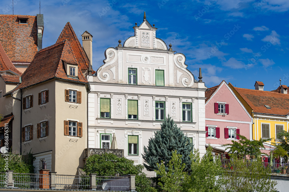 Obraz premium Historic step-gabled building and colorful traditional townhouses along the waterfront in Frohnleiten, Styria, Austria