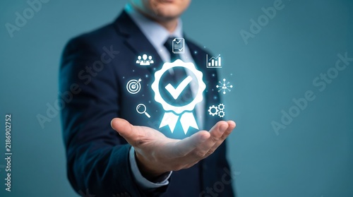 Businessman Hand Holding Quality Assurance Certification Seal Icon for Corporate Excellence Standards Compliance Graphic Layout Website Hero Header