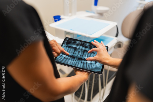 Obraz na plátně Dental professional discussing panoramic x ray on tablet with patient