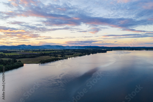 Aerial view across the expansive Clarence River beneath a soft pastel sky at dusk, with the broad waterway and surrounding landscape in northern New South Wales, Australia.