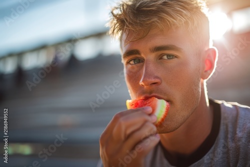 Young man enjoying a fresh apple slice in a bright outdoor setting capturing the joy of healthy living and tasty snacks. Generative AI