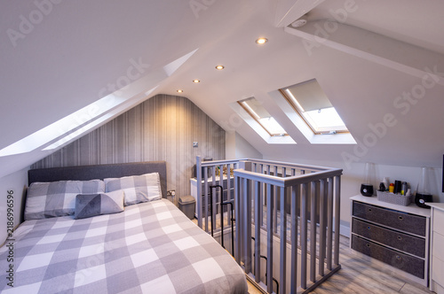 Quadro su tela Converted loft bedroom with double bed sloping white ceilings roof windows reces