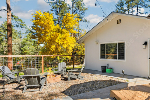 Backyard patio with Adirondack chairs and autumn trees