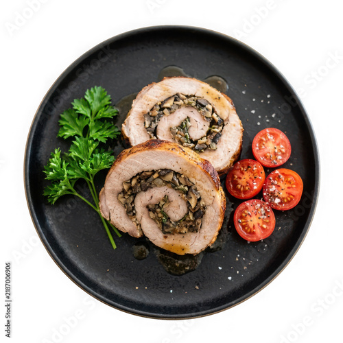Stuffed pork tenderloin roulade with mushrooms and herbs on a black plate isolated on transparent background