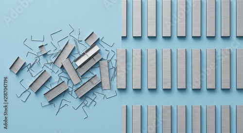 Obraz na płótnie Scattered and Organized Staples on Blue Background Showing Efficiency
