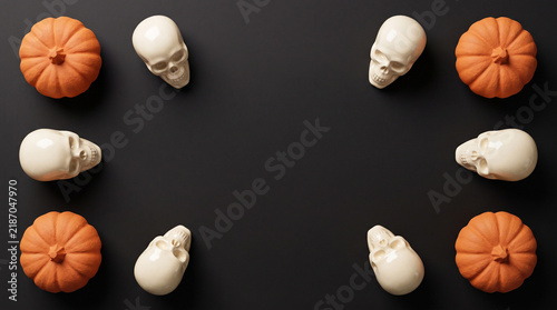 Halloween pumpkins and skulls symmetrical border flat lay on black background, spooky banner design with copy space