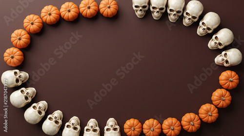 Halloween pumpkins and skulls oval border flat lay on brown background, spooky banner design with copy space