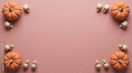 Halloween pumpkins and skulls corner layout flat lay on dusty pink background, spooky banner design with copy space