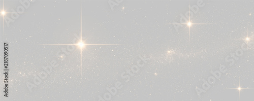 A cluster of bright golden stars shines against the deep black night sky. Countless tiny sparkling particles create a glowing cosmic dust effect. The image portrays a stunning celestial.