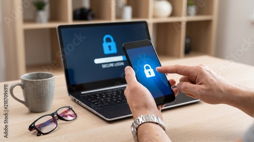 Person using a smartphone to authenticate a secure login on a laptop computer screen with uses smartphone access page laptop authentication cybersecurity communication business