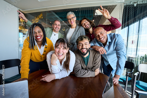 Multicultural coworkers laughing during a lively office meeting, showcasing teamwork, friendship, success, and a vibrant corporate atmosphere.
