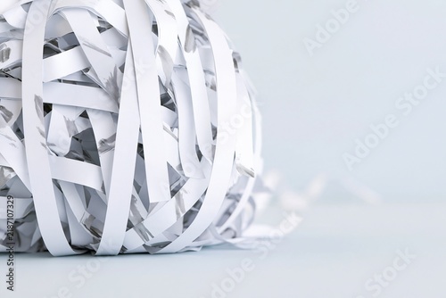 Coiled ball of shredded white documents on a minimal pale surface