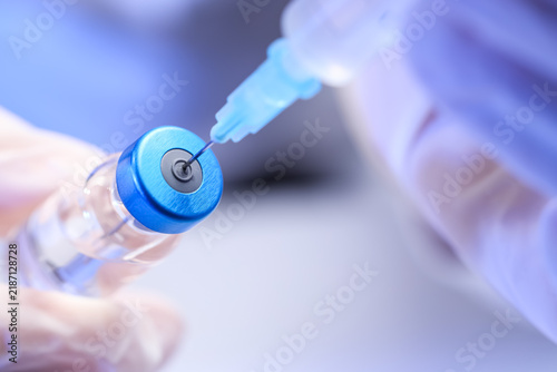 Vaccination and immunization  healthcare professional drawing medication from a glass vial with a syringe for medical treatment and disease prevention