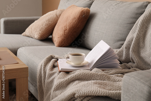 Relaxation and mindfulness, open book with coffee cup on a cozy sofa with sof...