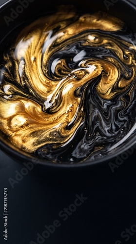 Close-up of mesmerizing black and gold liquid swirling together in an abstract, dynamic pattern, creating a visually rich and luxurious texture.