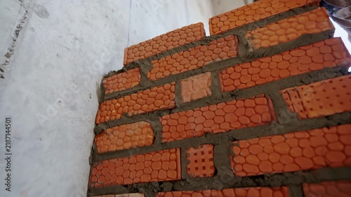 Builder hand removes excessive concrete mix from brickwork with mortar closeup. Worker makes wall inside building at bricklaying slow motion