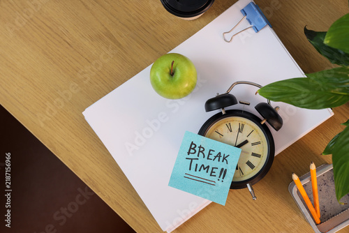Obraz na plátně Alarm clock and sticky note with text BREAK TIME, apple and stationery on table