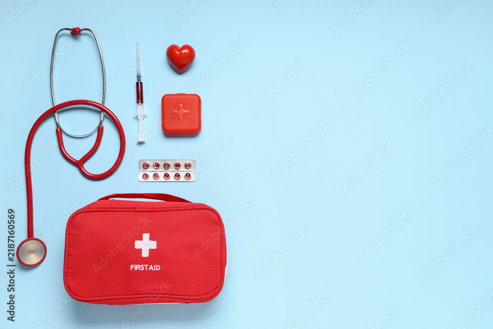 Obraz premium First aid kit with stethoscope, pills box, red heart and syringe on blue background