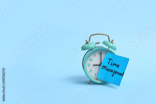 Foto Alarm clock and sticky note with text TIME MANAGEMENT on color background