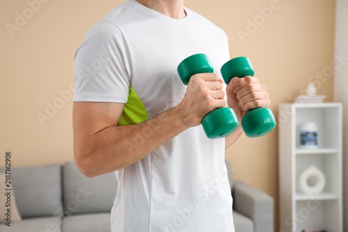 Sporty young man with dumbbells at home