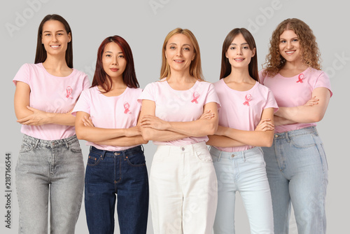 Beautiful women with pink ribbons on light background. Breast cancer awarenes...