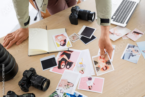Professional male photographer with modern cameras choosing photos on table i...