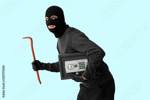 Konstfotografi Male thief with crowbar and safe box on blue background