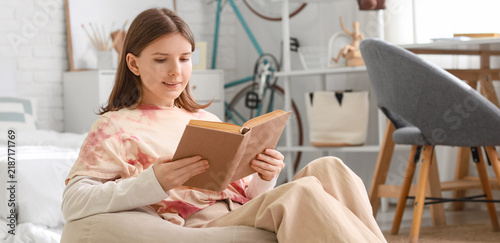Education and self-improvement, teenage girl reading a book at home for acade...