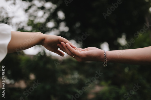 A close-up wedding photo of the newlyweds, the bride and groom touching each other with their hands and fingers.