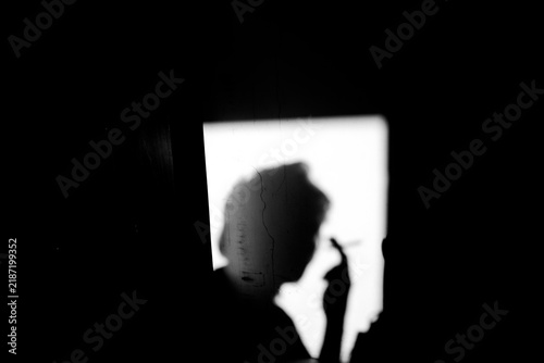 Close up side view black and white shadow of a man holding cigarette on the dirty wall