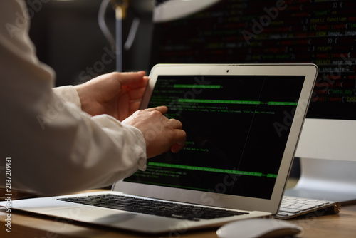 Female programmers hands working with laptop in office at night, closeup