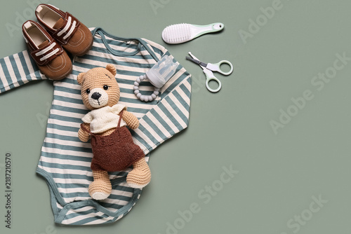 Baby care and newborn essentials  infant clothing with crochet teddy bear and accessories for parenting and childcare preparation on green background