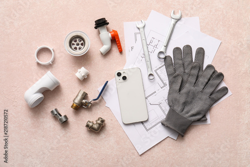 Set of plumbers items, mobile phone and house plans on pink grunge background