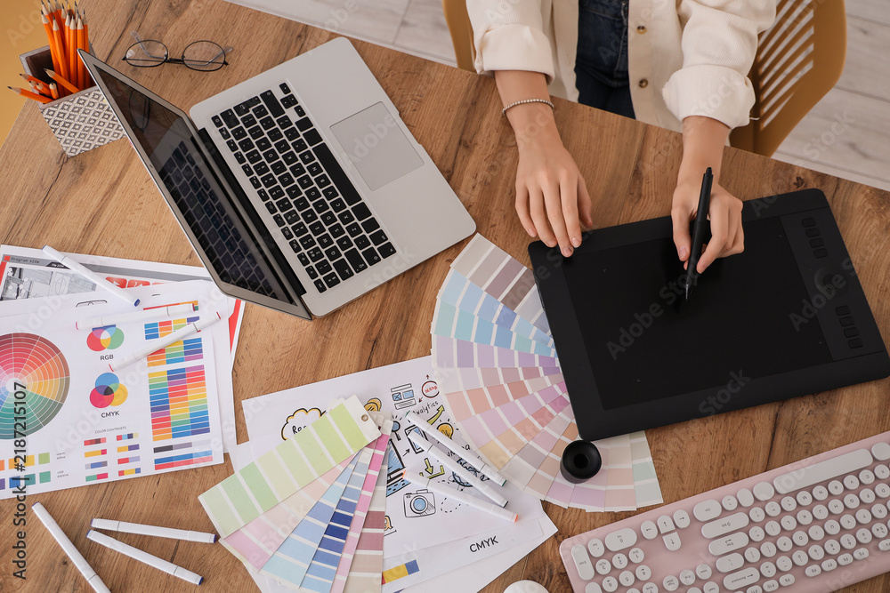 Obraz premium Female web designer with graphic tablet working at table in office, top view