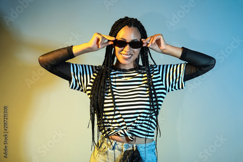 Cool young African-American woman with braids on color background