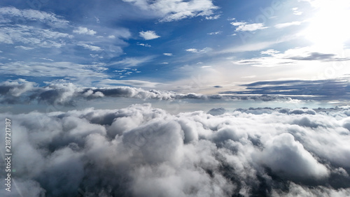 Aerial view of fluffy white clouds under a bright blue sky with sunlight filtering through the atmosphere in Sukabumi Regency, West Java, Indonesia.