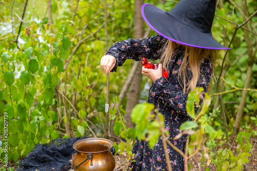 фотографія girl in black witch hat holding red glass potion bottle with heart stopper, litt