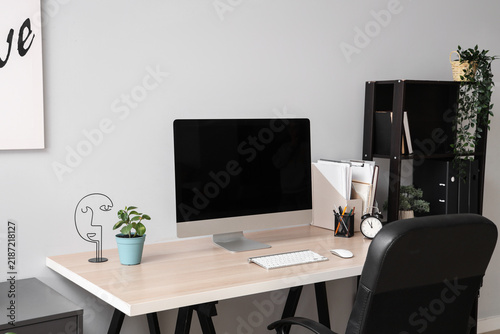Blank computer monitor with alarm clock on table in office