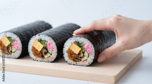 Obraz w ramie 節分の恵方巻きを手に取る女性の手元と和食の巻き寿司