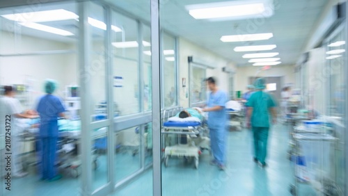 Blurred doctors and nurses walking in modern intensive care unit hallway abstract background with flowing shapes and lines