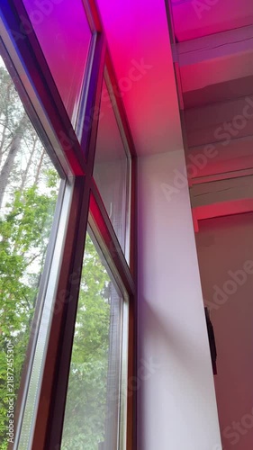 Multicolored LED accent lighting illuminates white wooden ceiling beams and the wall next to the tall windows. A low-angle view of the party interior. Vertical background with copy space