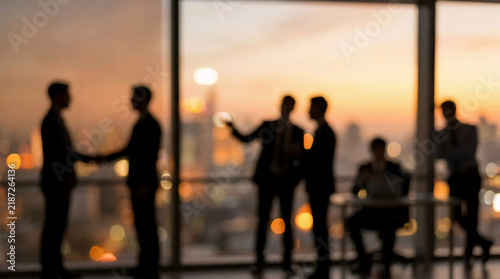 Blurred silhouettes of business professionals discussing in modern office with panoramic windows at sunset. AI generated