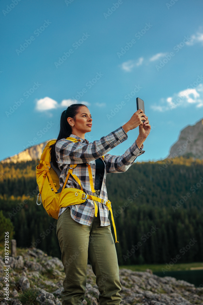 Obraz premium Woman hiking mountain taking selfie with smartphone