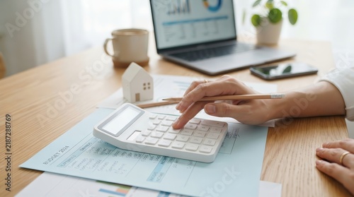Managing monthly expenses and savings using a calculator and laptop for budget planning.