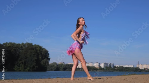 Tanned Female Model Enjoying Summer Vacation On Riverside Beach. Dancing And Relaxing In The Warm Sunshine.