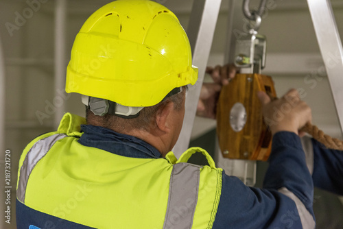 Fotografie Merchant vessel crew member seen from behind performing routine work duties on the deck of a commercial ship, illustrating maritime operations and life at sea