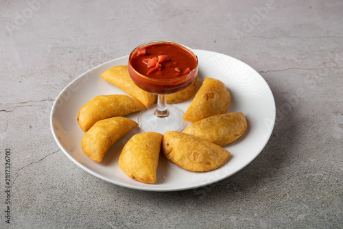 Fried Colombian corn empanadas served with spicy red sauce dip